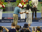 Linda is presenting Chair Umpire Fergus Murphy with a commemorative plaque
