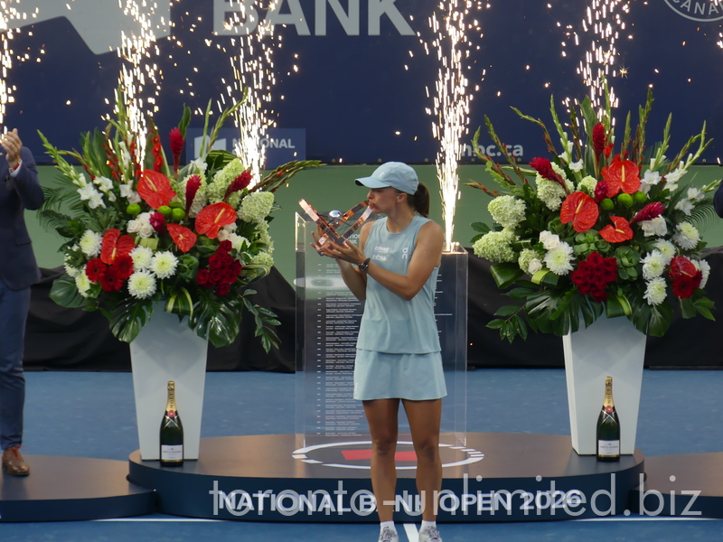 Happy Iga Swiatek is kissing her Trophy with the fireworks behind 