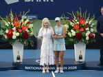 Iga Swiatek is holding her Trophy to pose with Susan Rogers