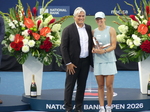 Iga Swiatek is holding her Trophy and posing with Karl Hale,