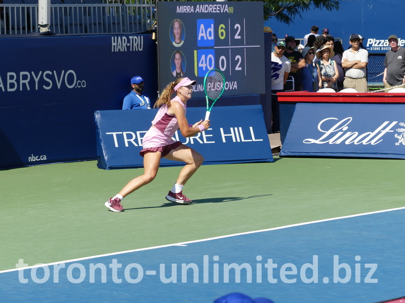 Running Mirra Andreeva chasing the ball behind the baseline.