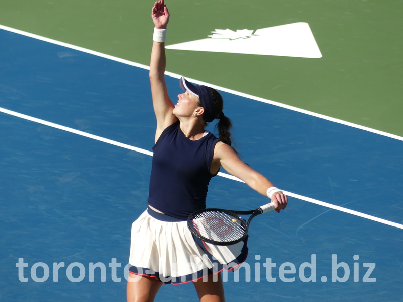 Kayla Day is tossing the ball high to serve.