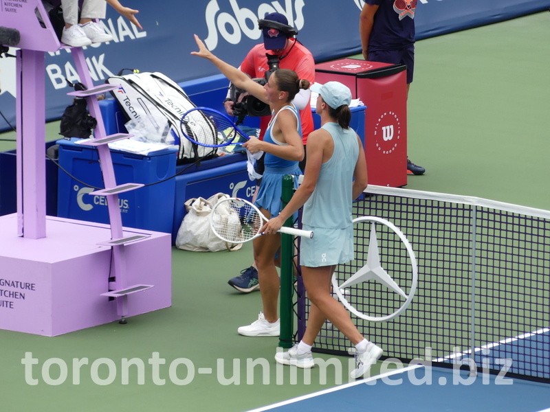 Iga Swiatek has won the match and walks with Marta Kostyuk to shake hands with the umpire.