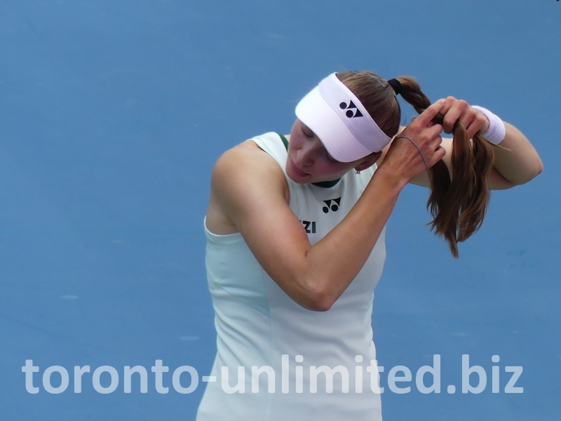 A close-up of Elena Rybakina while she fixes her hairdo on the Court during the changeover.