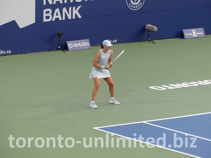 Observing the play, Iga Swiatek stands behind the baseline. 