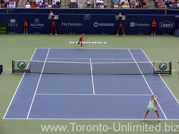 Elena Dementieva serving in far court against Maria Sharapova in front.