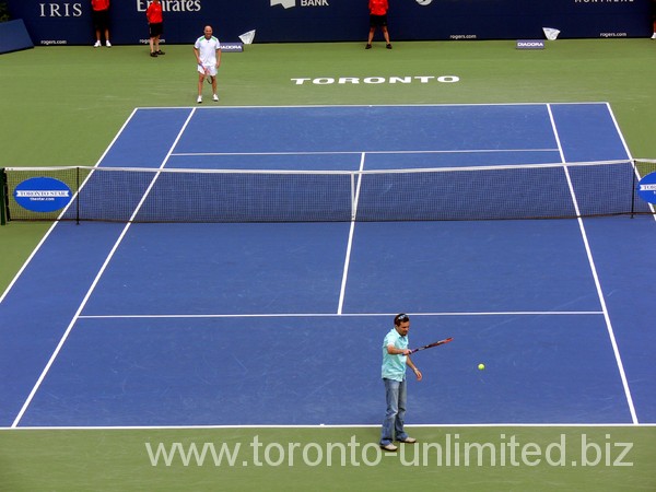 Spectator serving against Andre Agassi on the court