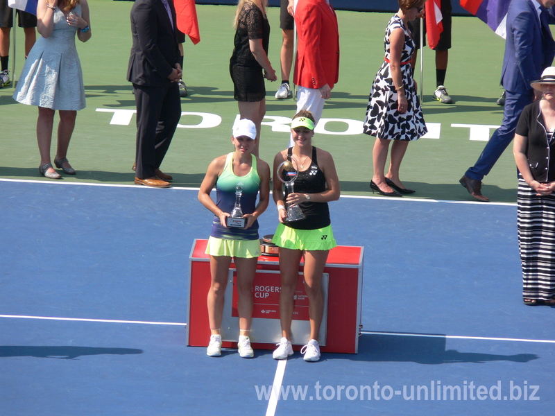 Belinda Bencic and Simona Halep are holding and displaying their trophies on Centre Court after the singles final 16 August 2015 Rogers Cup Toronto